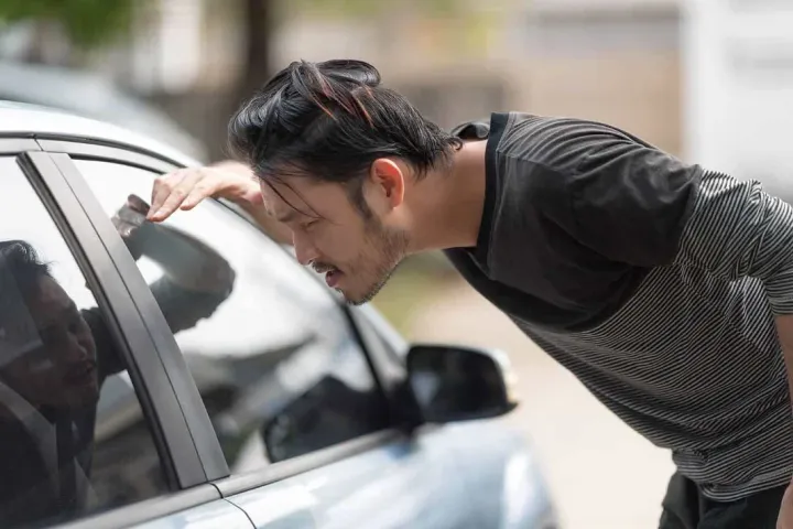 Driver locked out of a car, waiting for an automotive locksmith